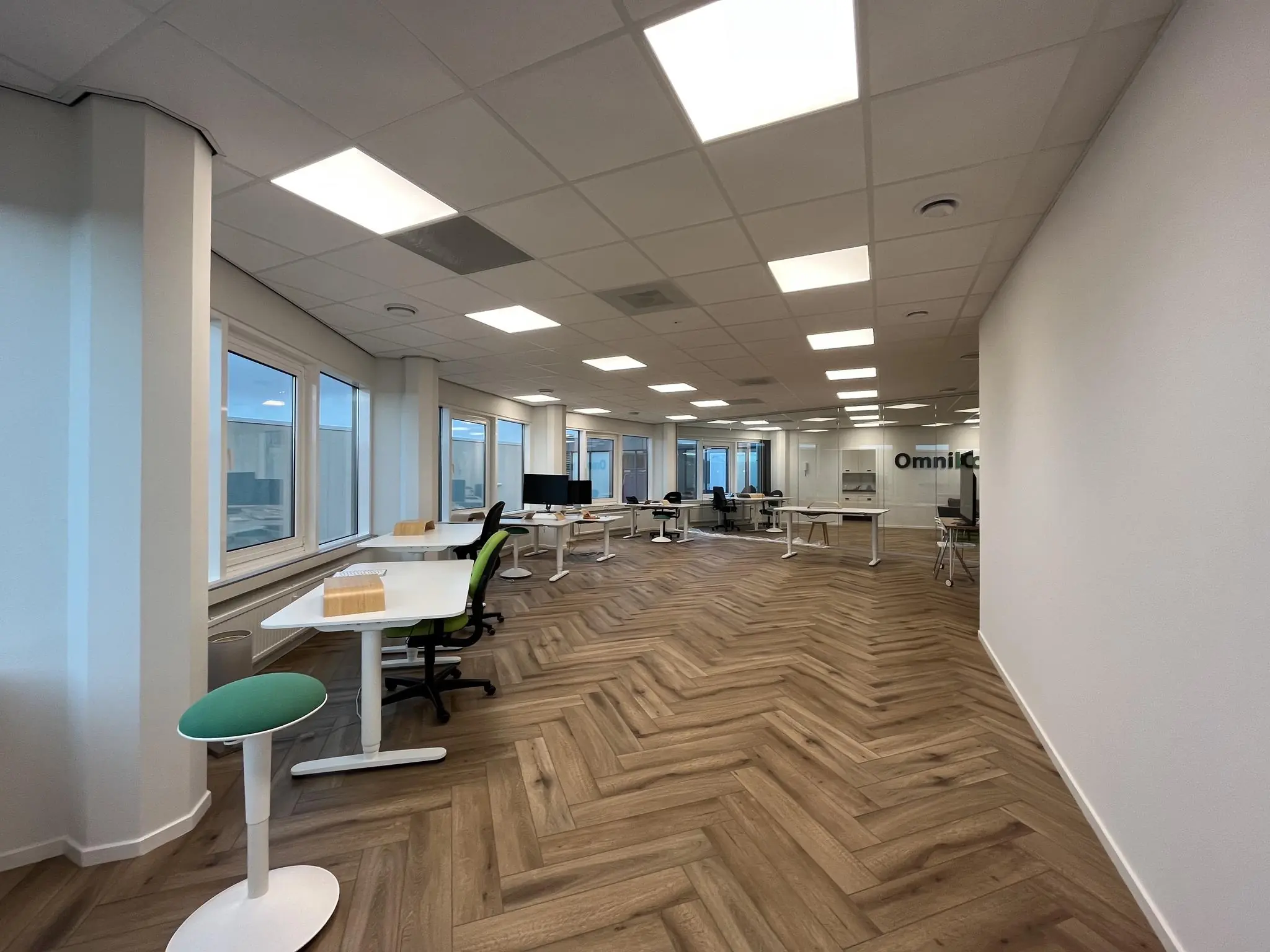 Modern kantoorpand aan de Lange Dreef met open werkplekken, glazen wanden en visgraat houten vloer.